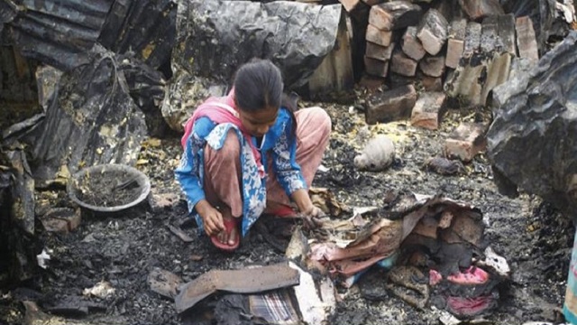 পুড়ে যাওয়া ঘরে কিছু একটা খুঁজছে একজন বাসিন্দা